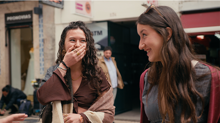 Two women laughing together on a city street.
