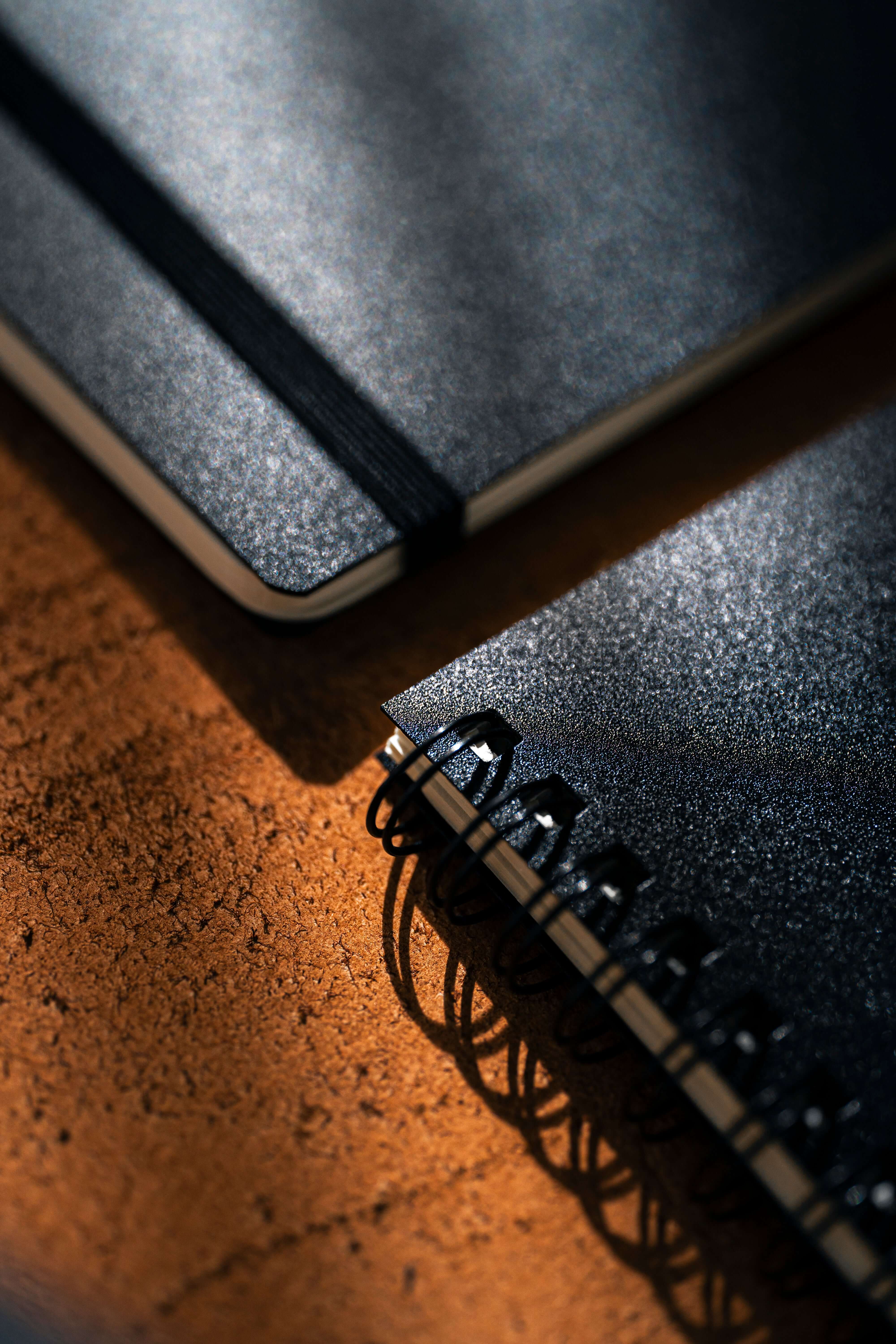 Close-up of two stylish notebooks, one with a strap and the other spiral bound, showcasing the REPLICA: Pocket-size Impression Pad.