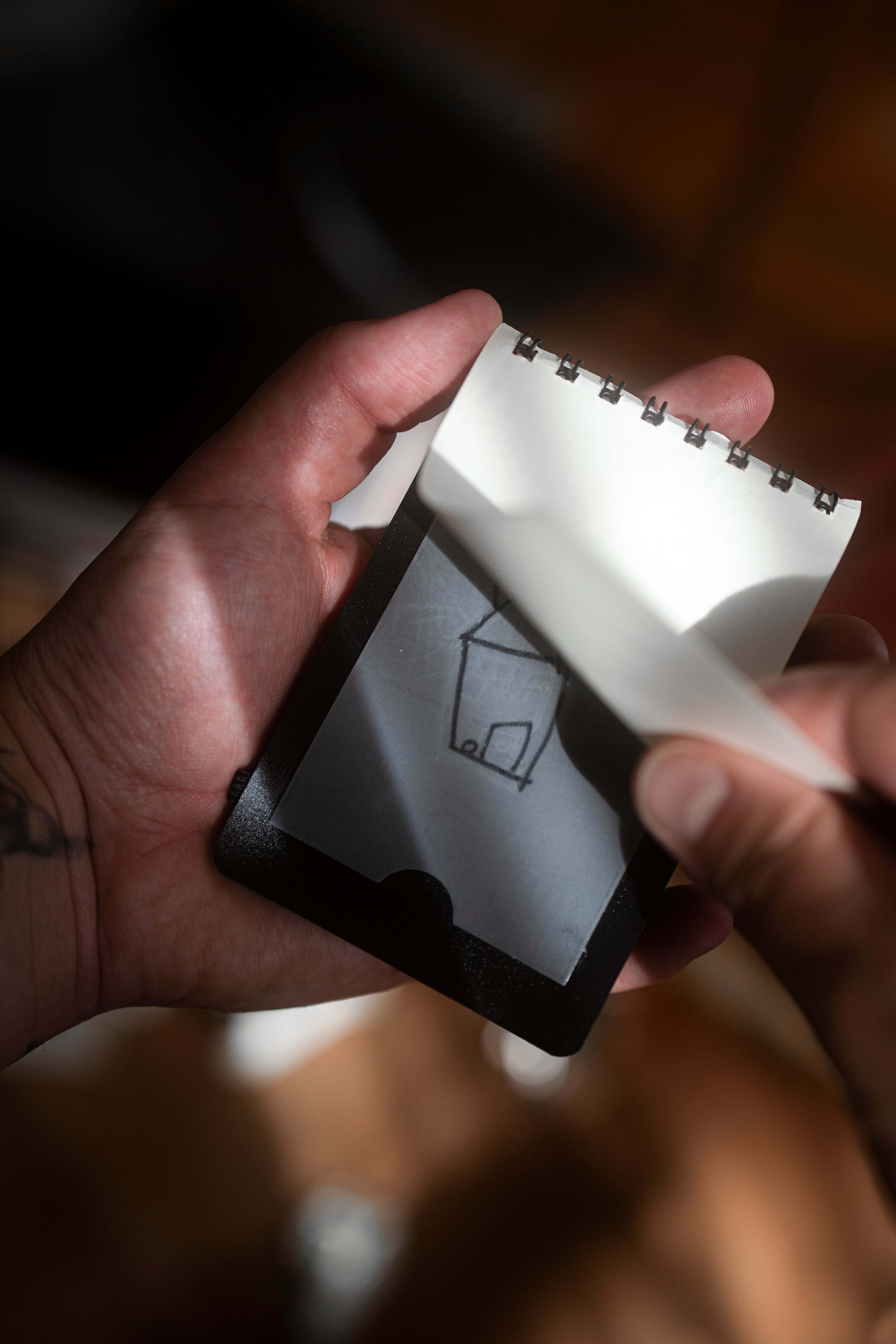 Hand holding the REPLICA: Pocket-size Impression Pad with a drawing revealed.