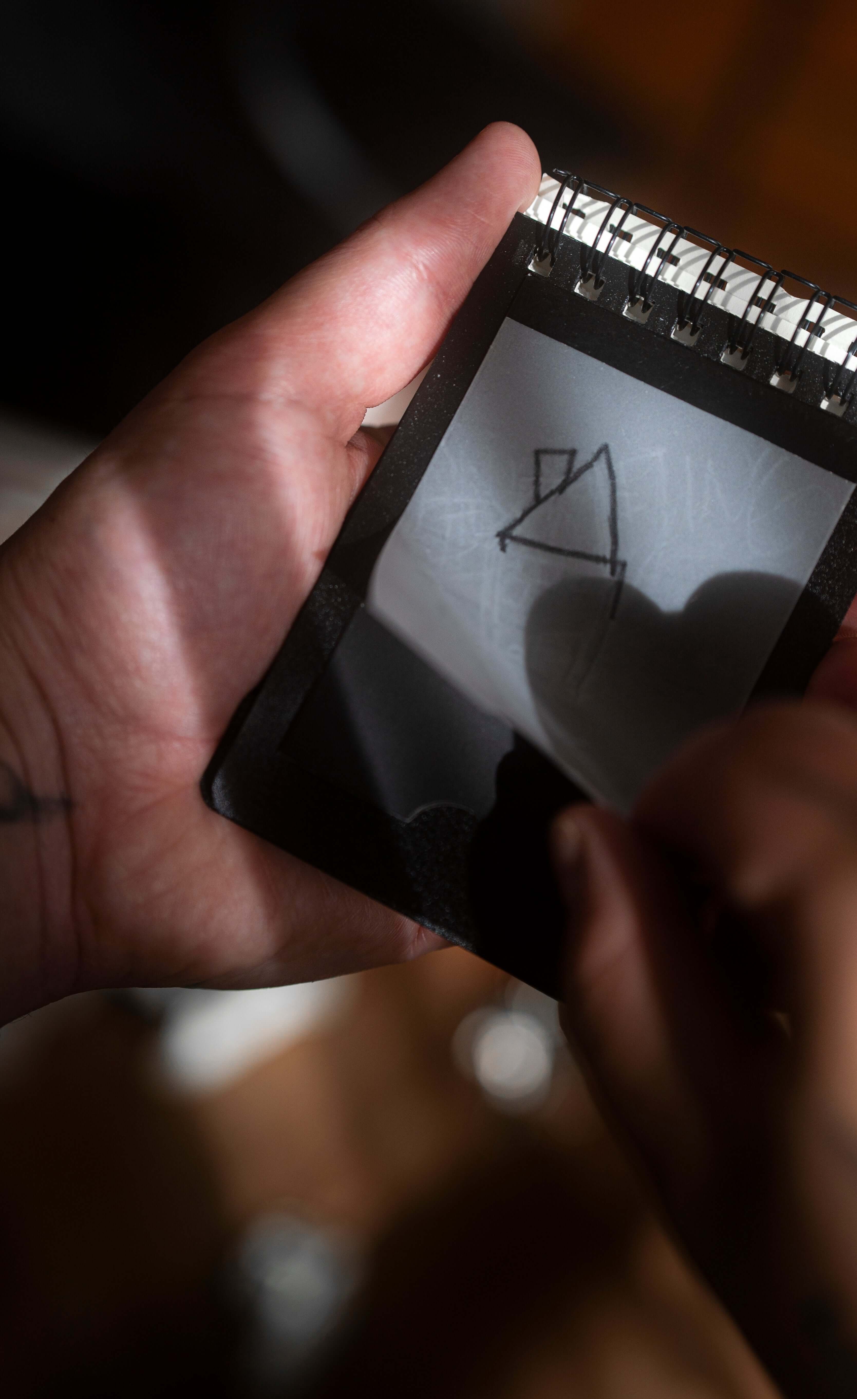 Hands using REPLICA: Pocket-size Impression Pad to create a secret drawing.